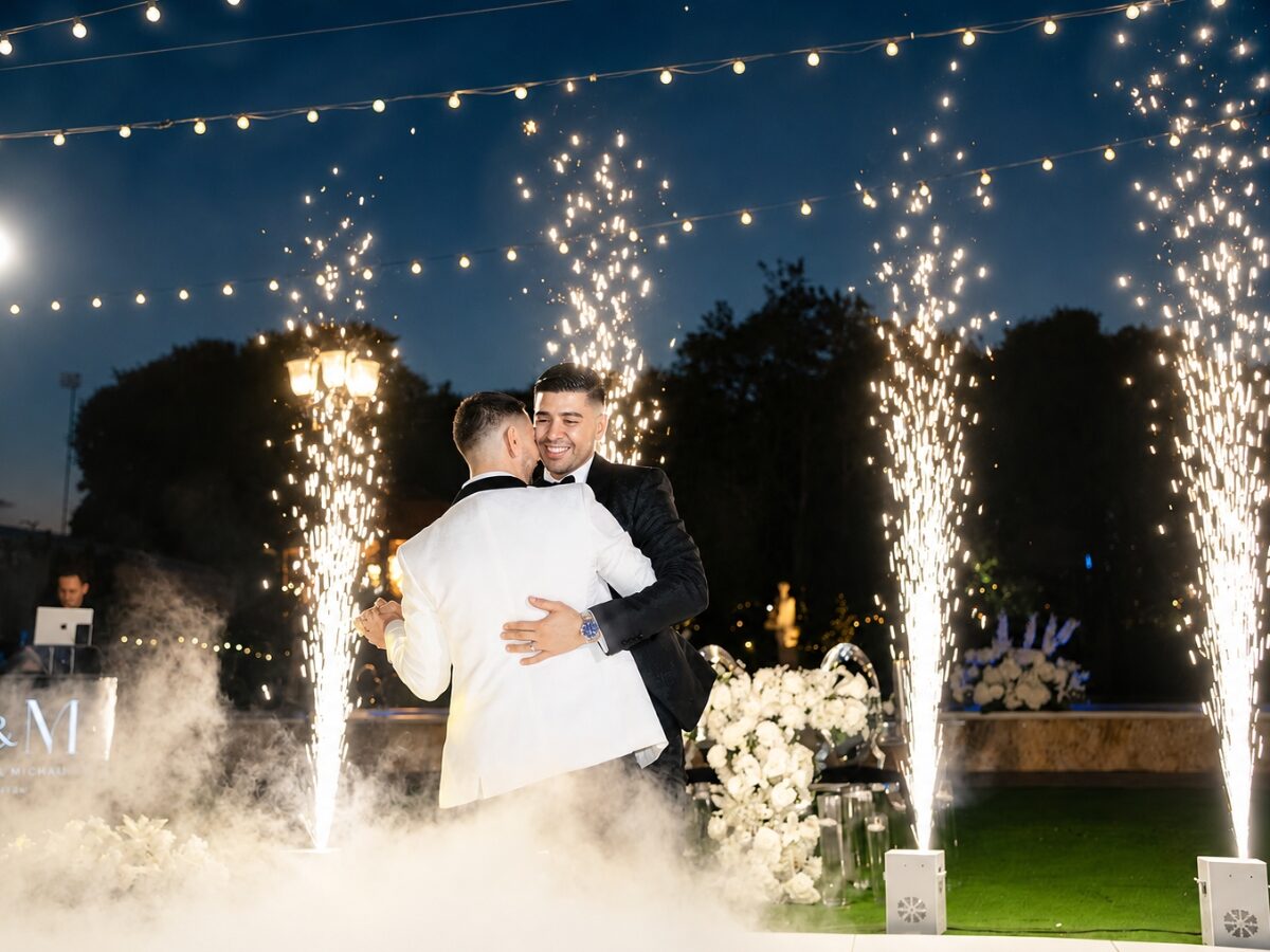 Pareja bailando en las nubes mientras chispas frías caen detrás de ellos en su boda