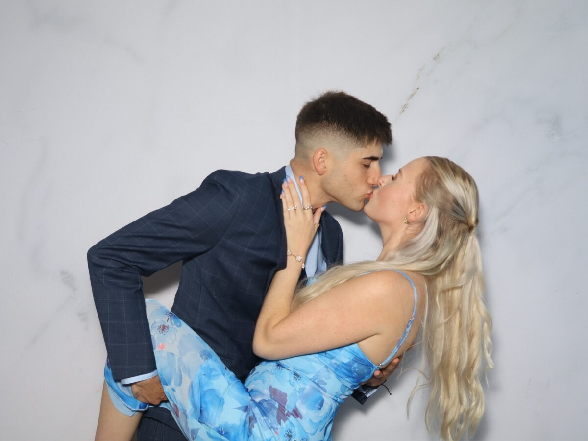Pareja posando con carteles en la cabina de fotos de la boda