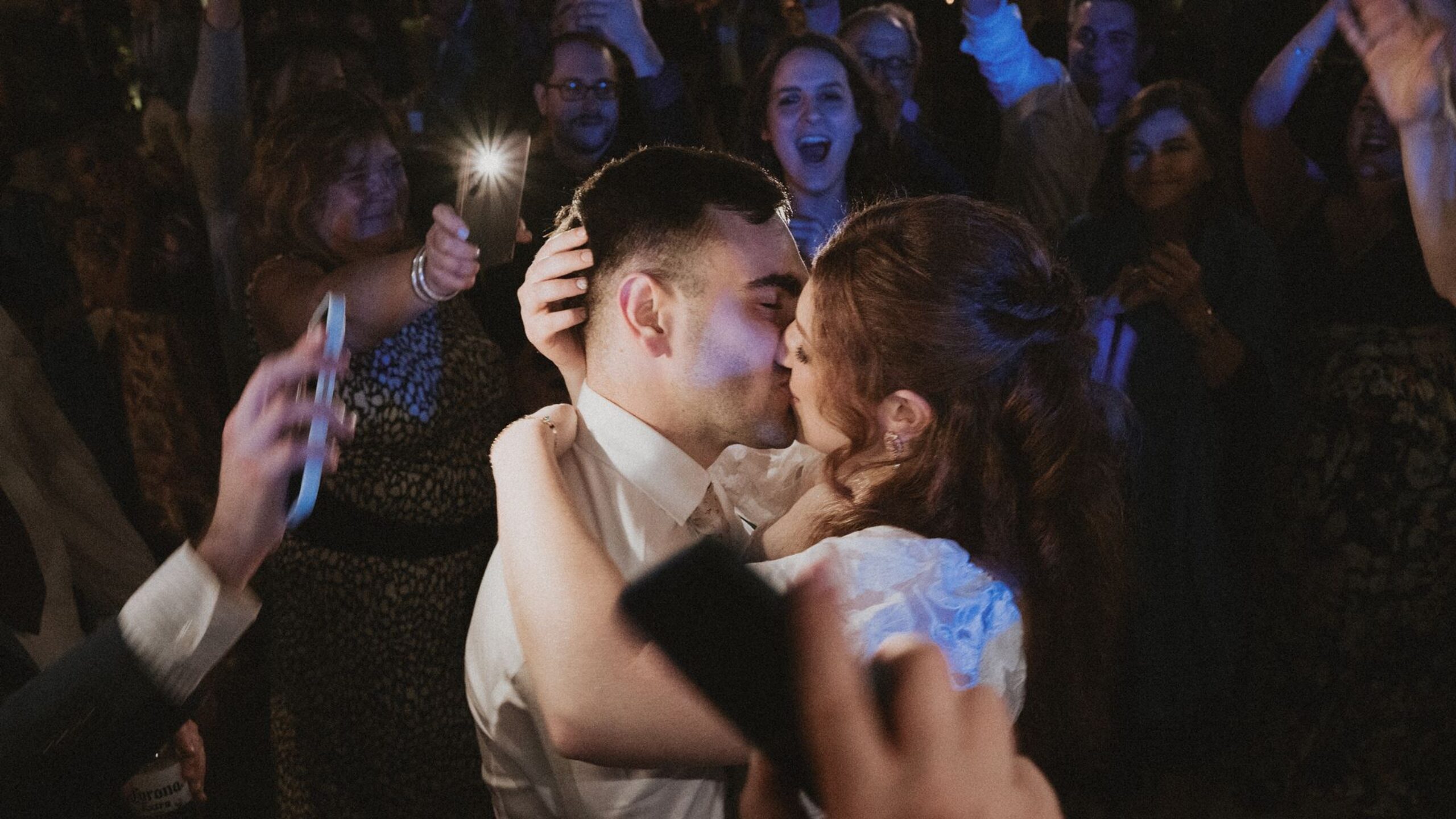 Novios besándose en medio de la pista de baile rodeados de sus seres queridos