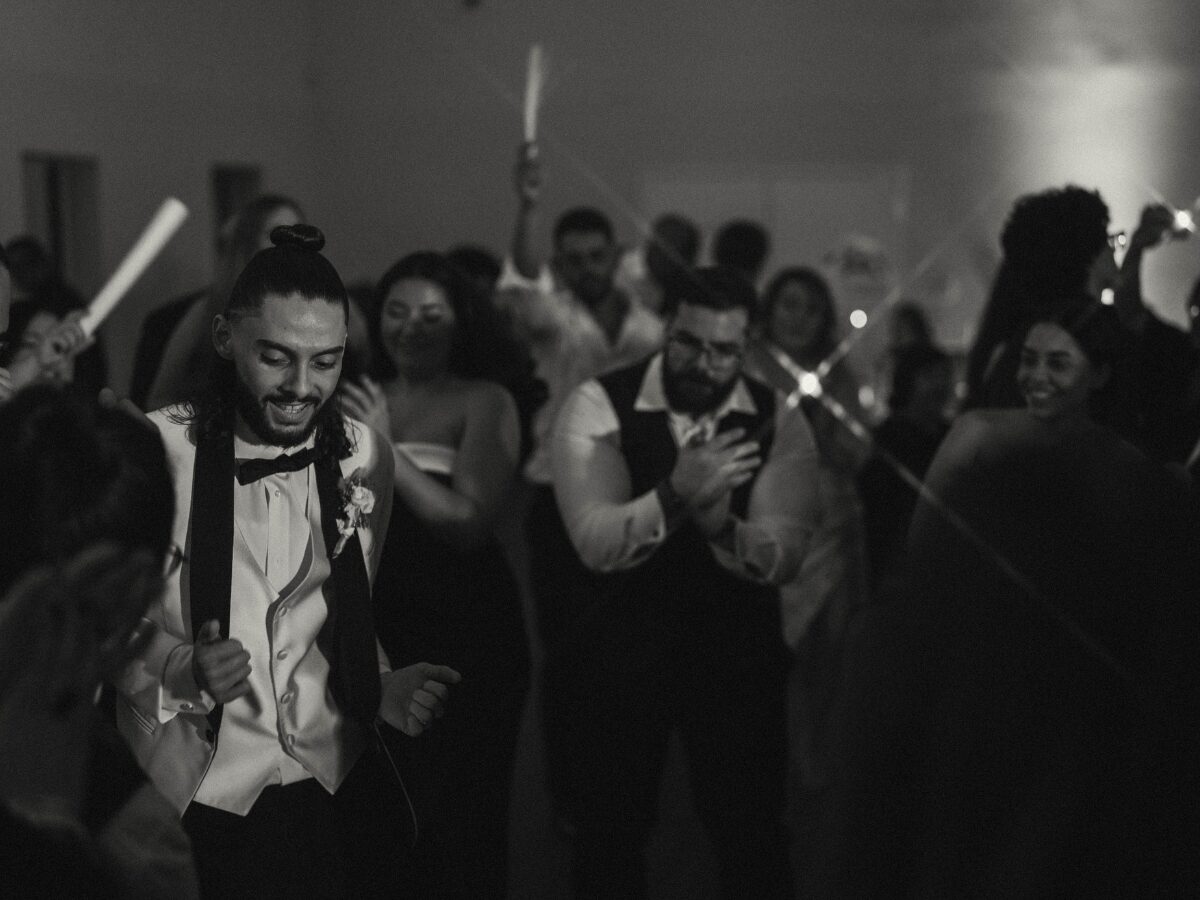 Novio bailando con los invitados en la pista de baile de la boda en blanco y negro
