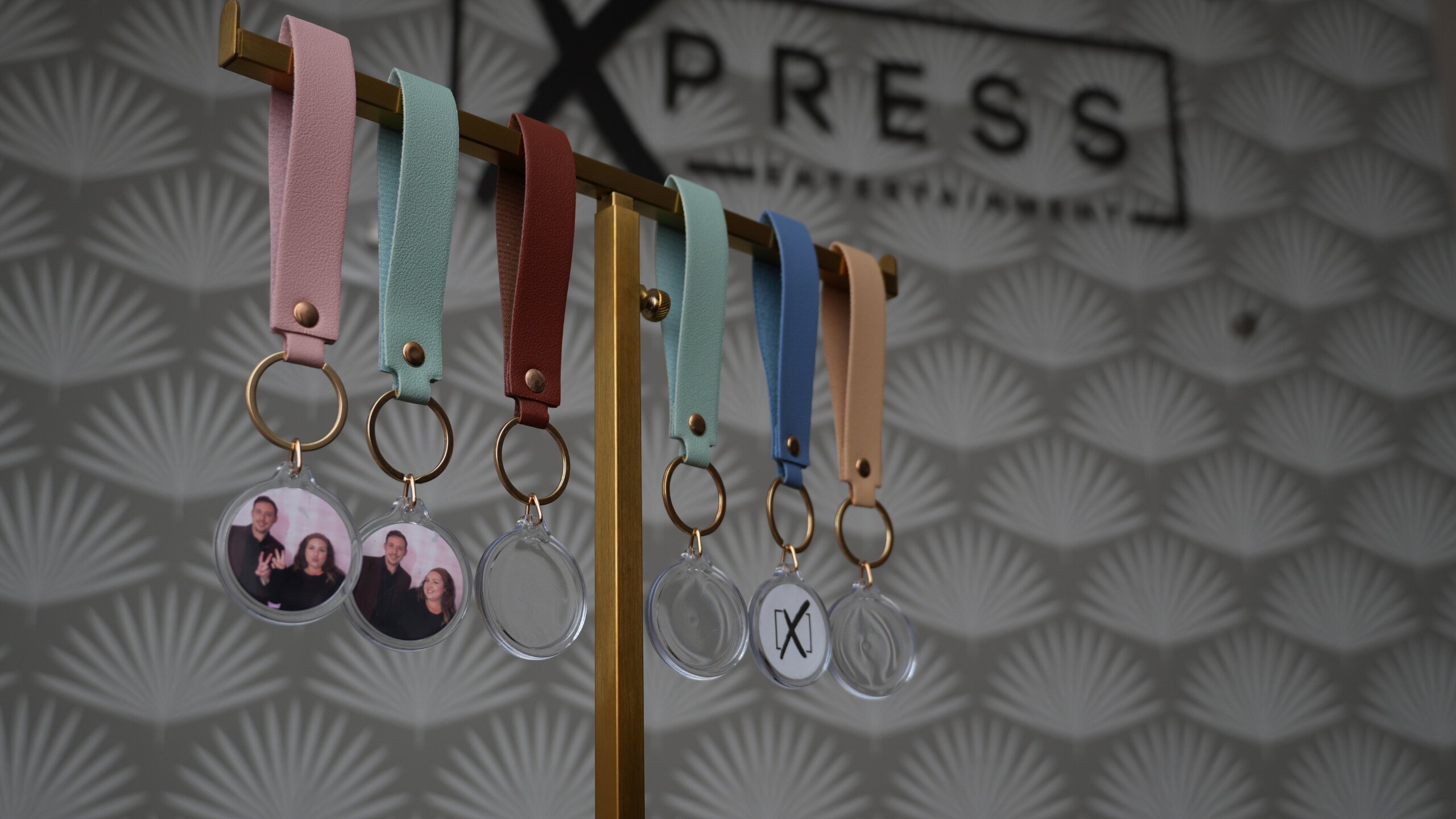 Custom leather wedding keychains with gold hardware and photo inserts from the Xpress Entertainment Keychain Station