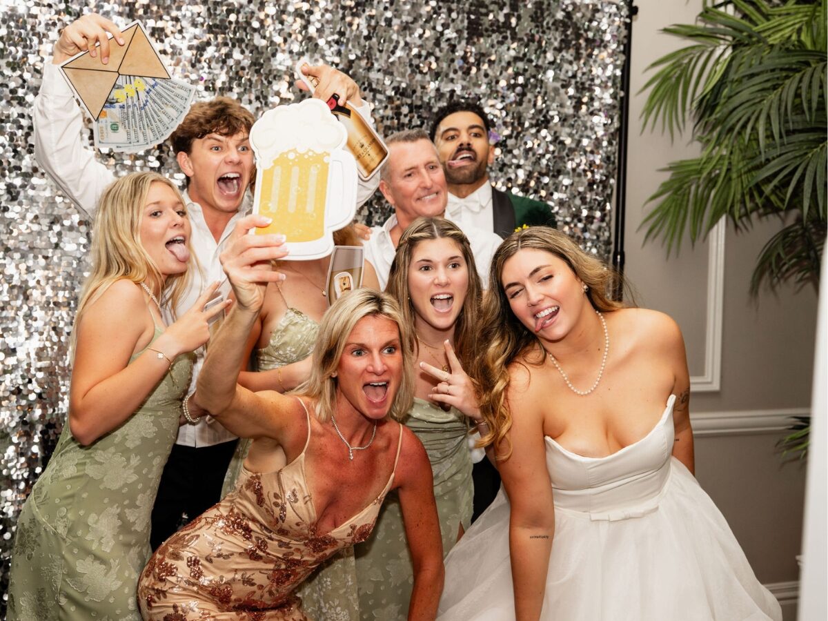 Una pareja disfrutando de su cabina de fotos con amigos en su boda en Jupiter