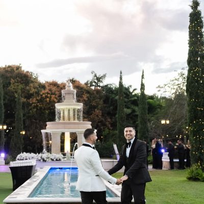 Couple holding hands in front of the fountain during their wedding reception at Villa Toscana Miami in Homestead, Florida.