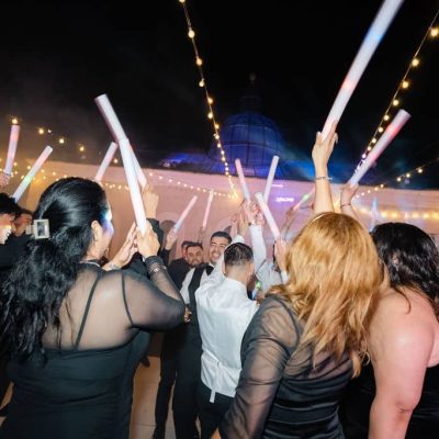 Wedding guests celebrating with LED foam sticks on the packed dance floor at Villa Toscana Miami reception.
